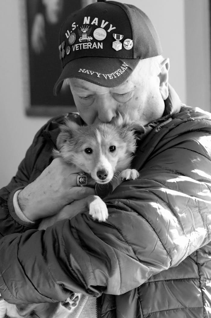 Man in Black Hat Hugging White and Brown Dog